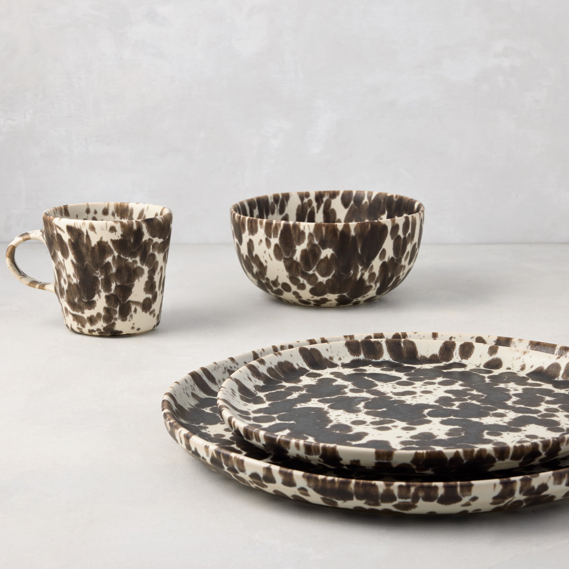 Nuno Splatter stoneware dinner plate set with brown spots on a cream base, including a mug and bowl.