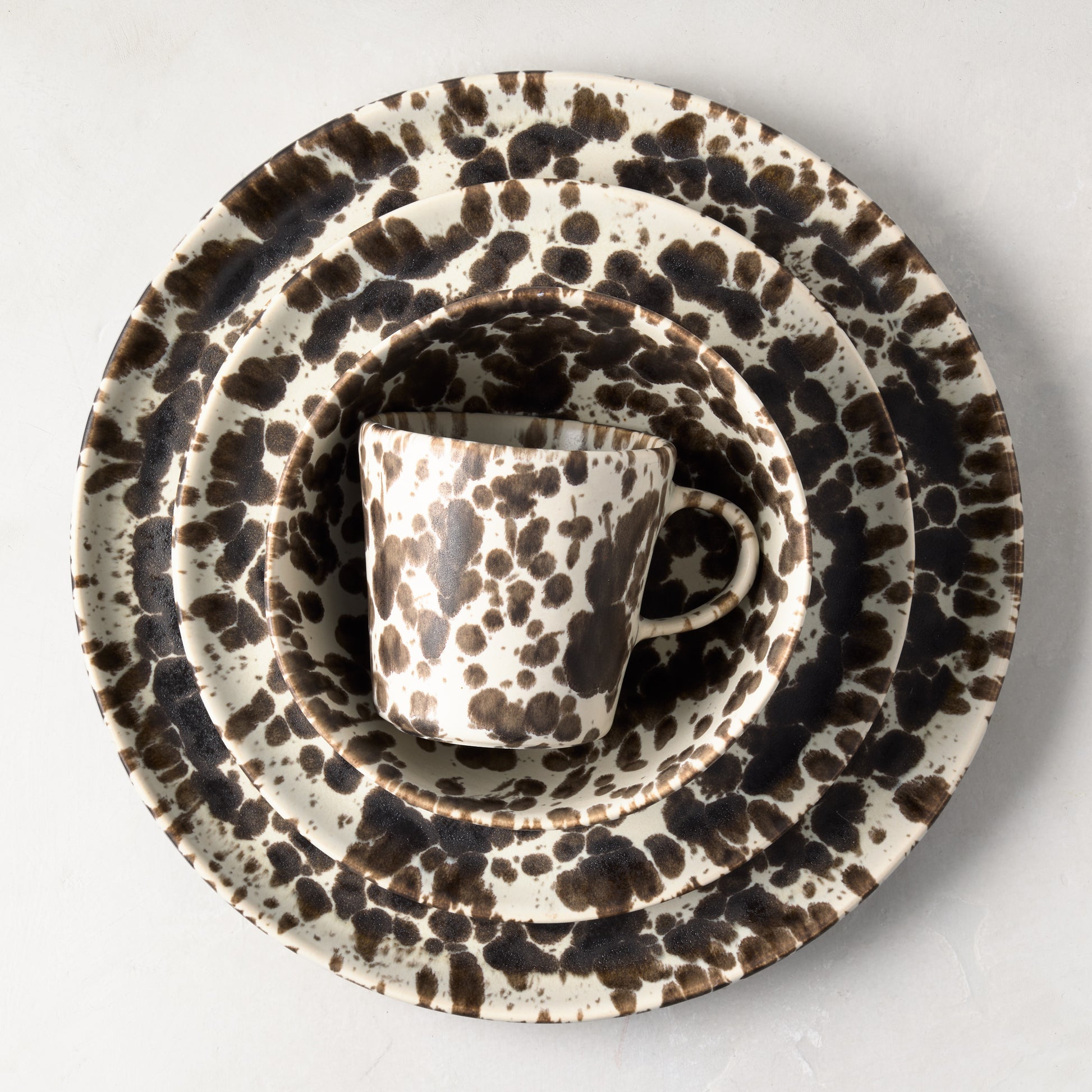 Nuno Splatter stoneware dinner plate set with brown spots on cream, including a mug, bowl, and two plates.