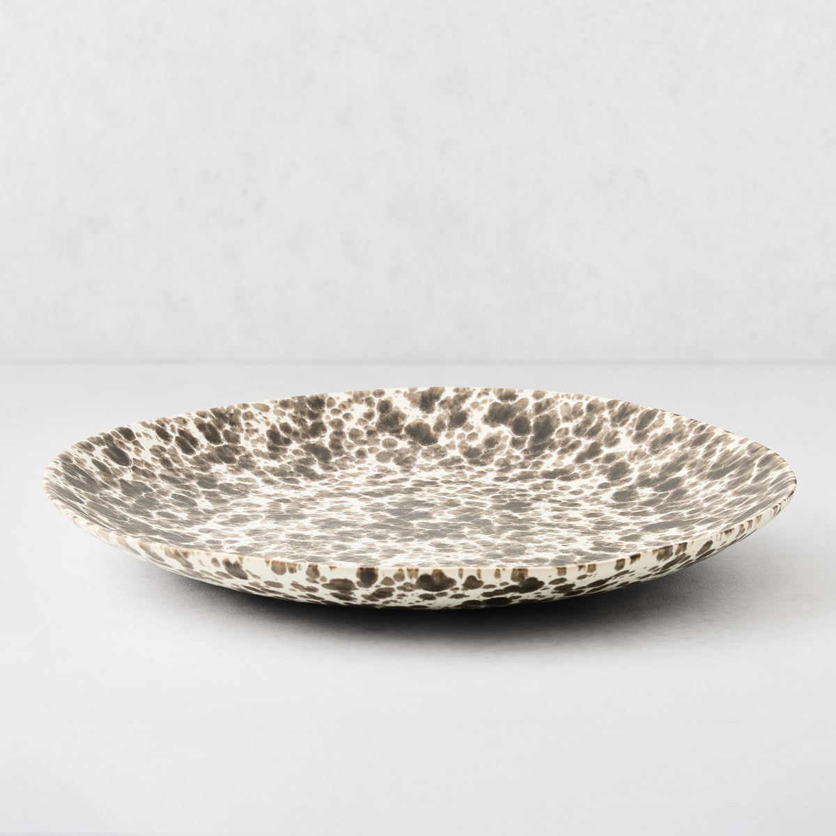 Nuno Splatter Stoneware Round Serve Platter, pale cream with unique brown splatter pattern.