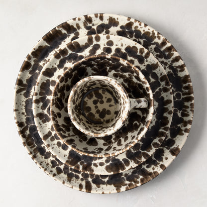 Nuno Splatter stoneware salad plate with brown spots on a pale cream base, nested with matching dinnerware.