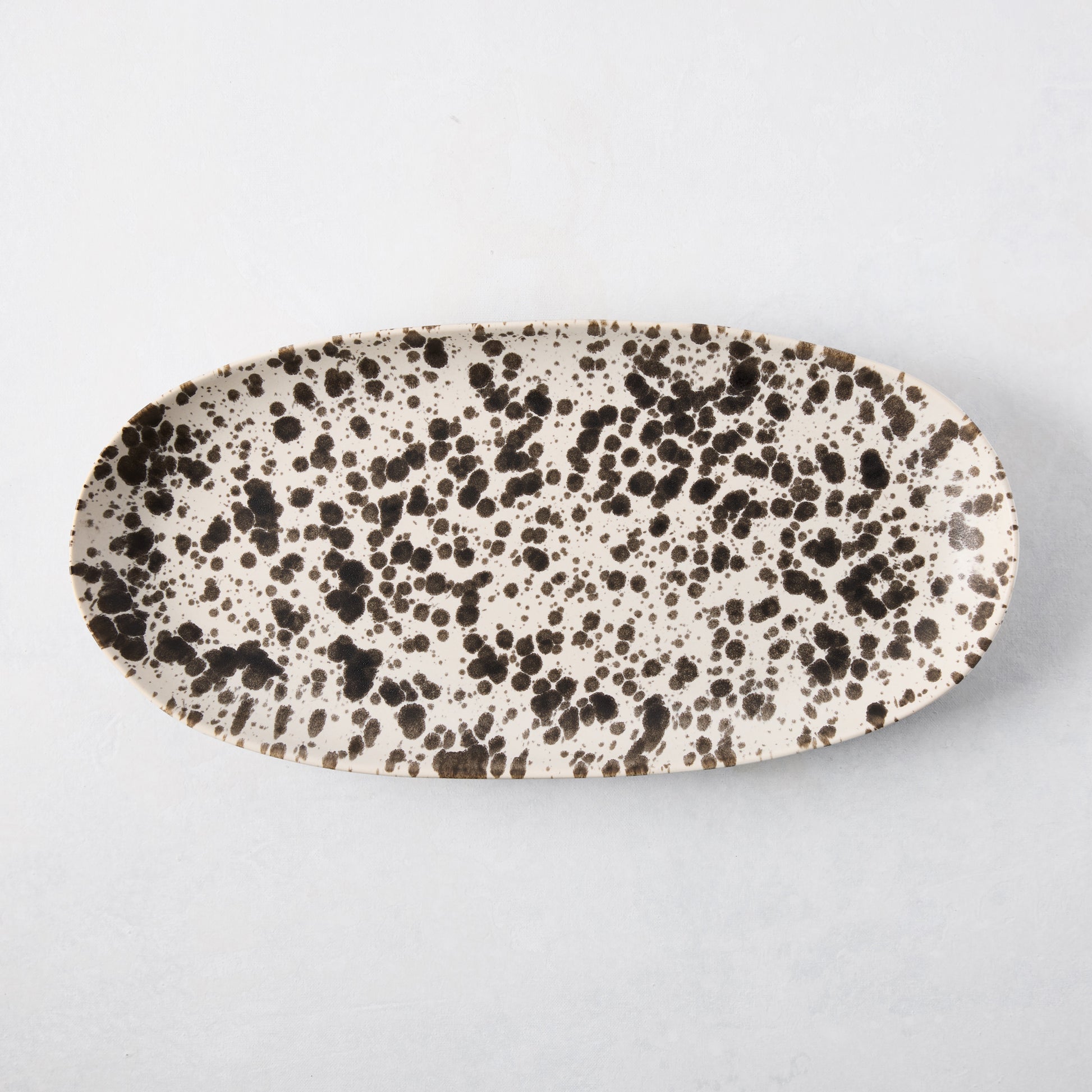 Nuno Splatter oval stoneware serving platter, pale cream with unique brown splatter design.