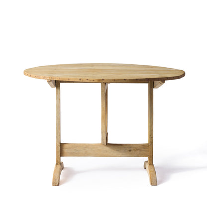 Vintage French bleached oak wine tasting table with a round top and trestle base on a white background.