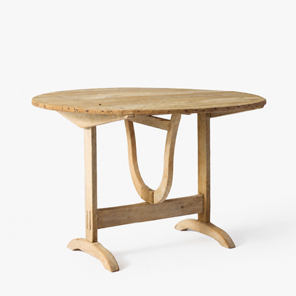 Vintage bleached oak wine tasting table with a round top and unique trestle base on a white background.