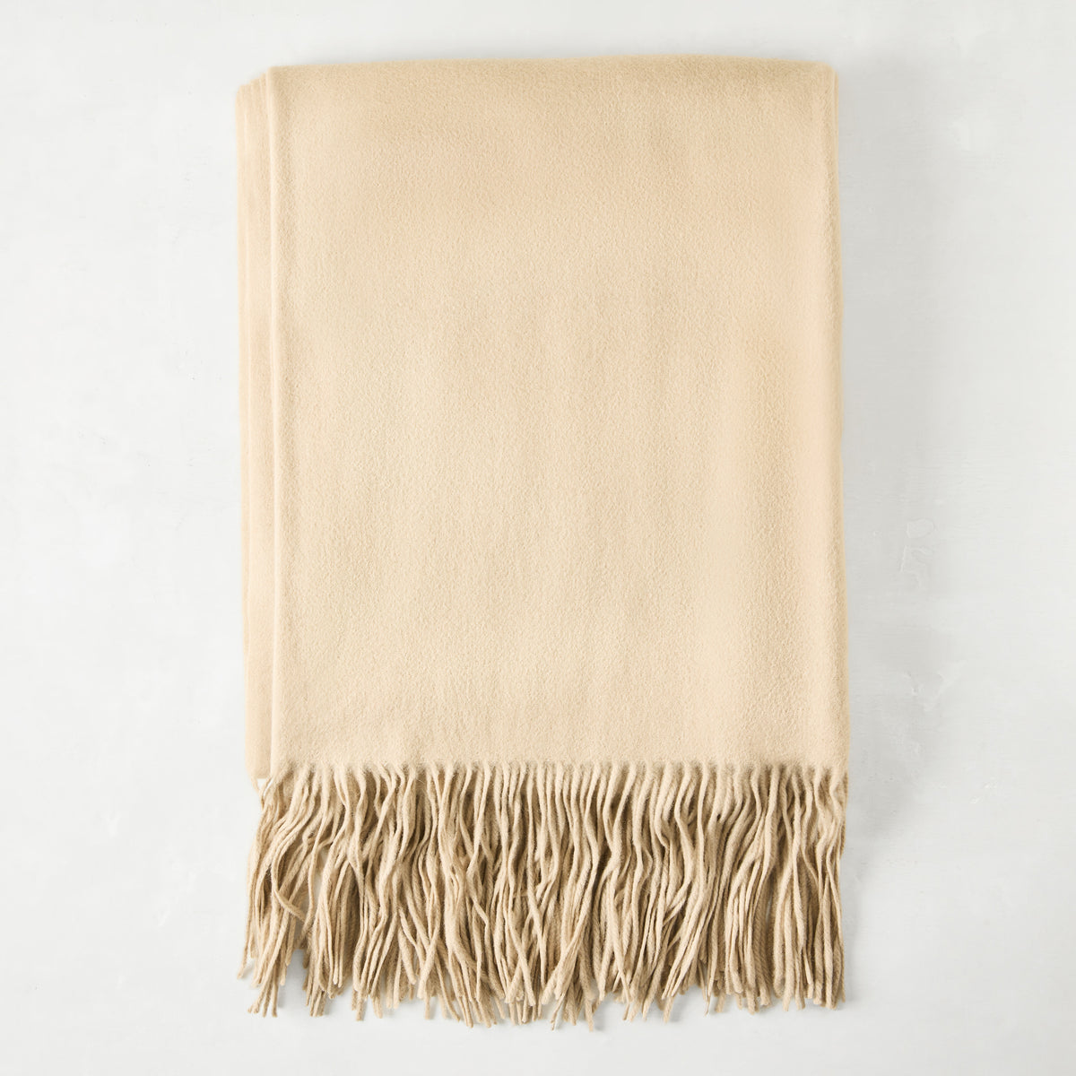 Folded Oat Cashmere Throw Blanket with classic fringe.