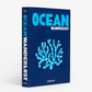 Ocean Wanderlust" book: navy blue linen hardcover with light blue and silver coral illustration.