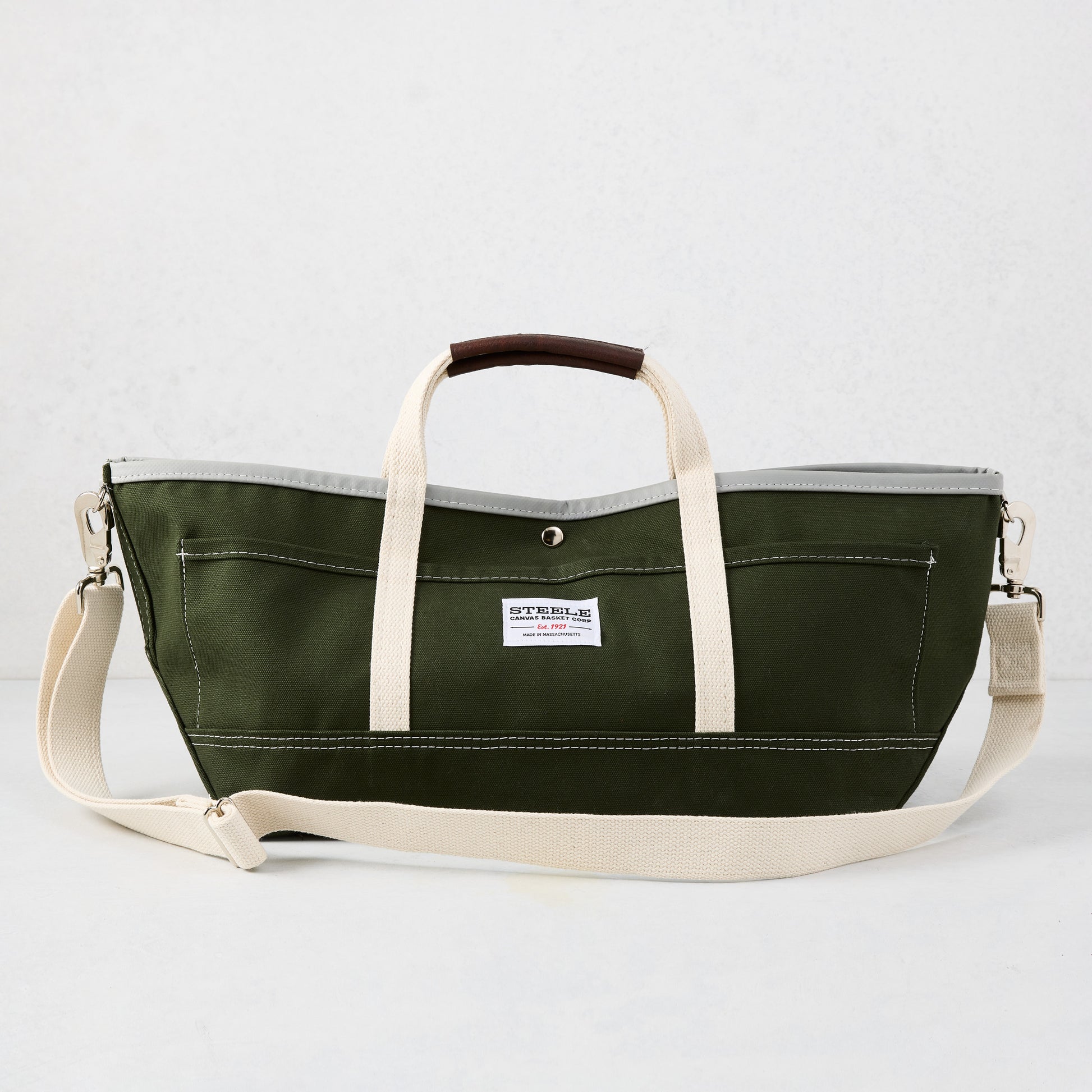 Olive green canvas garden tote bag with cream straps, brown leather handle grips, and a gray interior lining.