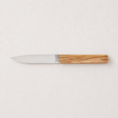 Perceval 9.47 stainless steel knife with a natural olive wood handle on a light textured background.