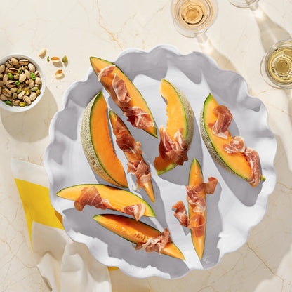 White Onda Round Ceramic Serving Platter with cantaloupe and prosciutto, pistachios, and wine.