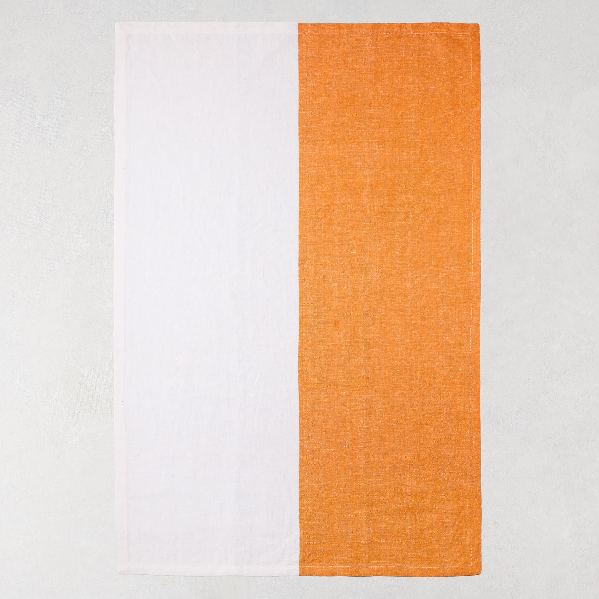 Orange and white block print cotton-linen hand towel, half orange, half white.