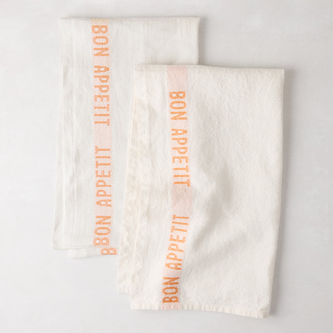 Set of 2 white linen hand towels with vertical orange "Bon Appetit" text.