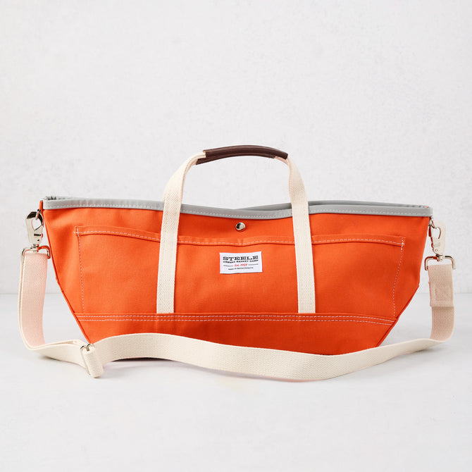 Orange canvas garden tote bag with cream straps, leather grips, and gray interior lining.