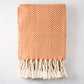 Folded orange and white chevron cotton throw blanket with thick rope fringe.