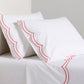 White organic cotton percale sheet set with orange double scallop stitch embroidery on pillows and flat sheet.