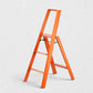 Hudson Grace orange Hasegawa Lucano 3-step ladder with a minimalist aluminum and steel design and non-skid feet.