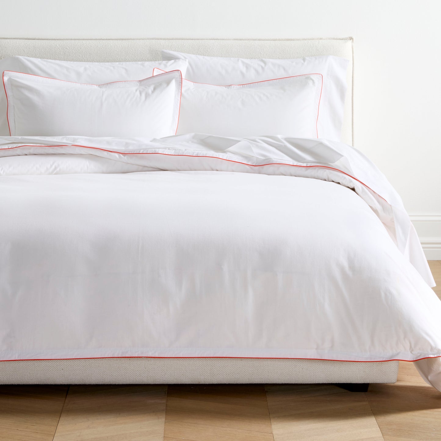 White percale duvet set with orange piping and double-stitch detailing on a bed.