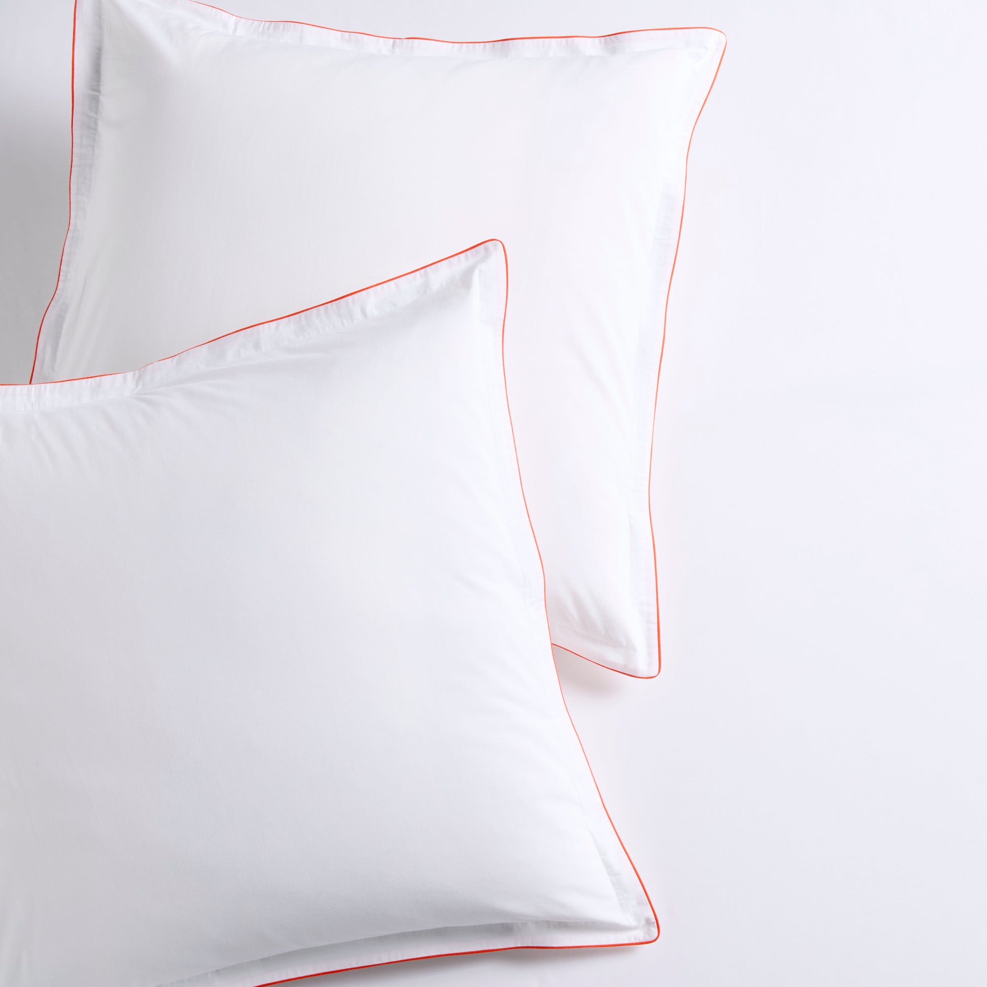 Set of 2 white percale Euro shams with orange piping and double-stitch detailing.