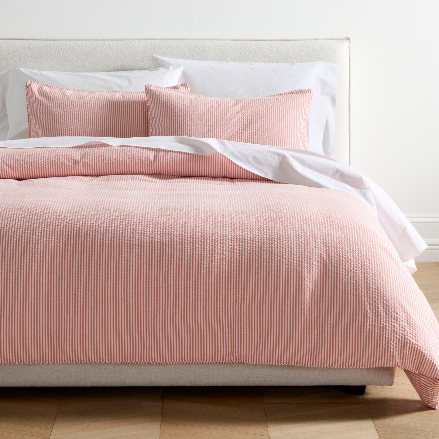 Orange seersucker stripe organic cotton duvet set with two shams on a bed.