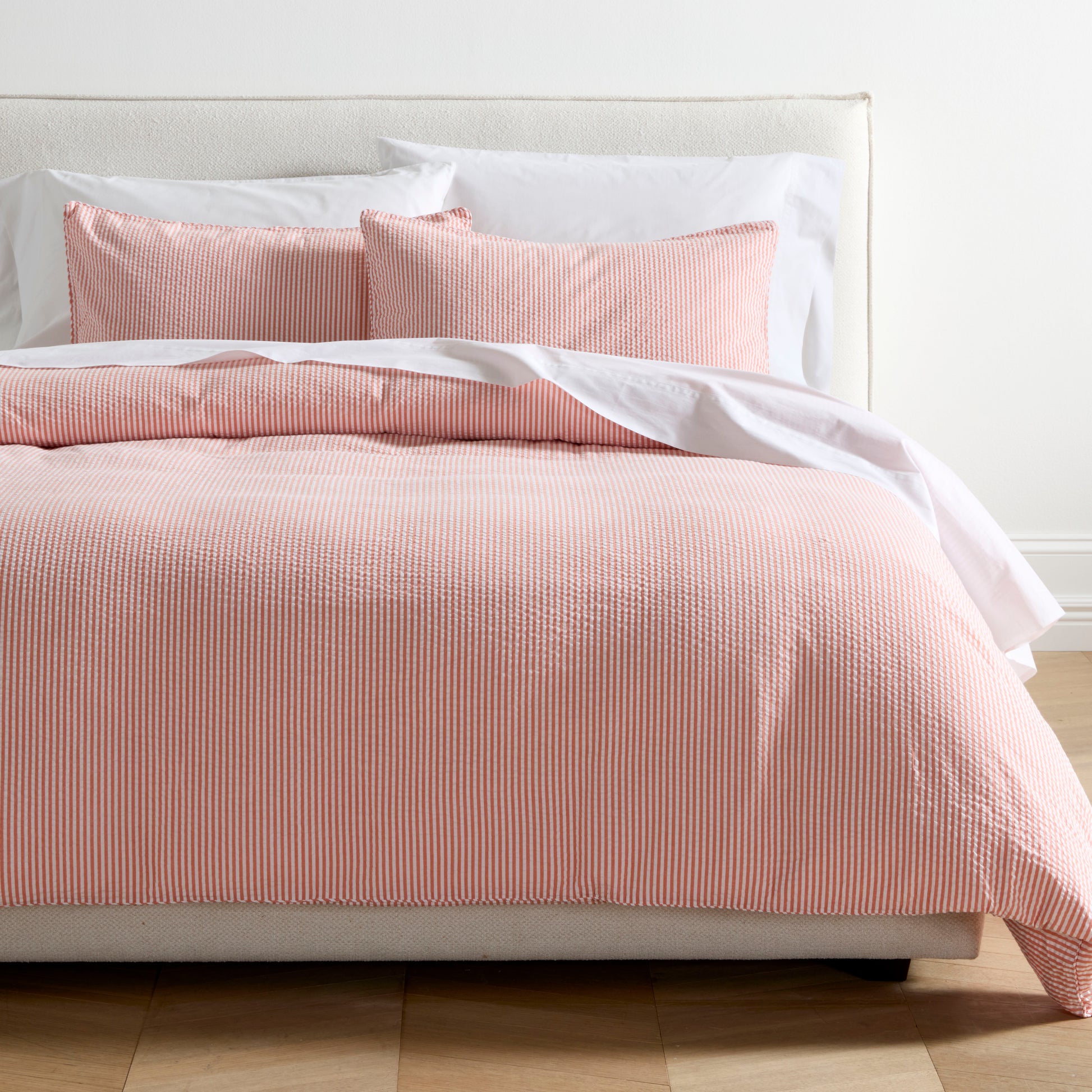 Orange seersucker stripe organic cotton duvet set with two shams on a bed.