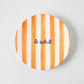 Hand-painted ceramic "Le Soleil" appetizer plate with bright orange stripes and navy blue text.
