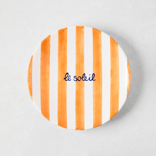 Hand-painted ceramic "Le Soleil" appetizer plate with bright orange stripes and navy blue text.