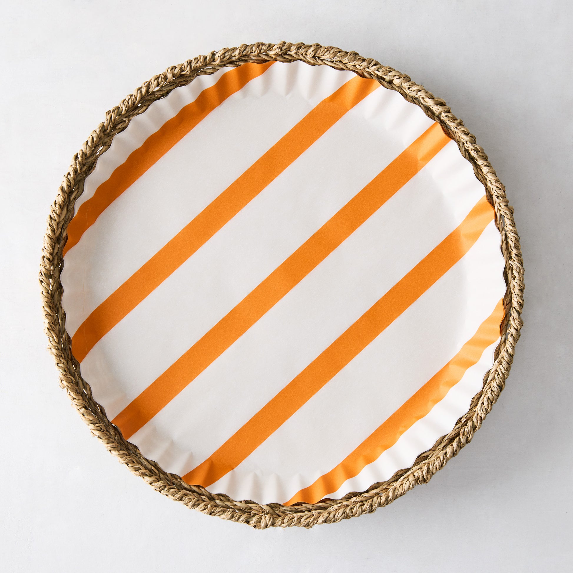 Round parchment liner with orange diagonal stripes inside a woven wicker tray.