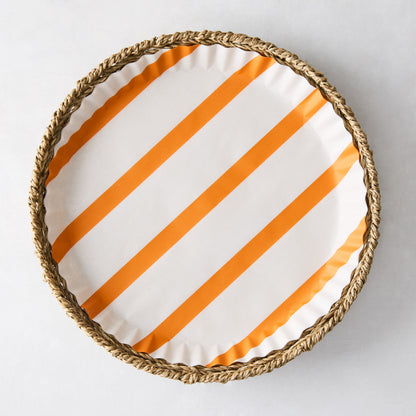 Round parchment liner with orange diagonal stripes inside a woven wicker tray.