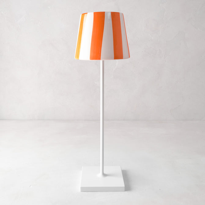 Hand-painted ceramic lamp shade with orange and white stripes on a white Poldina Pro lamp base.