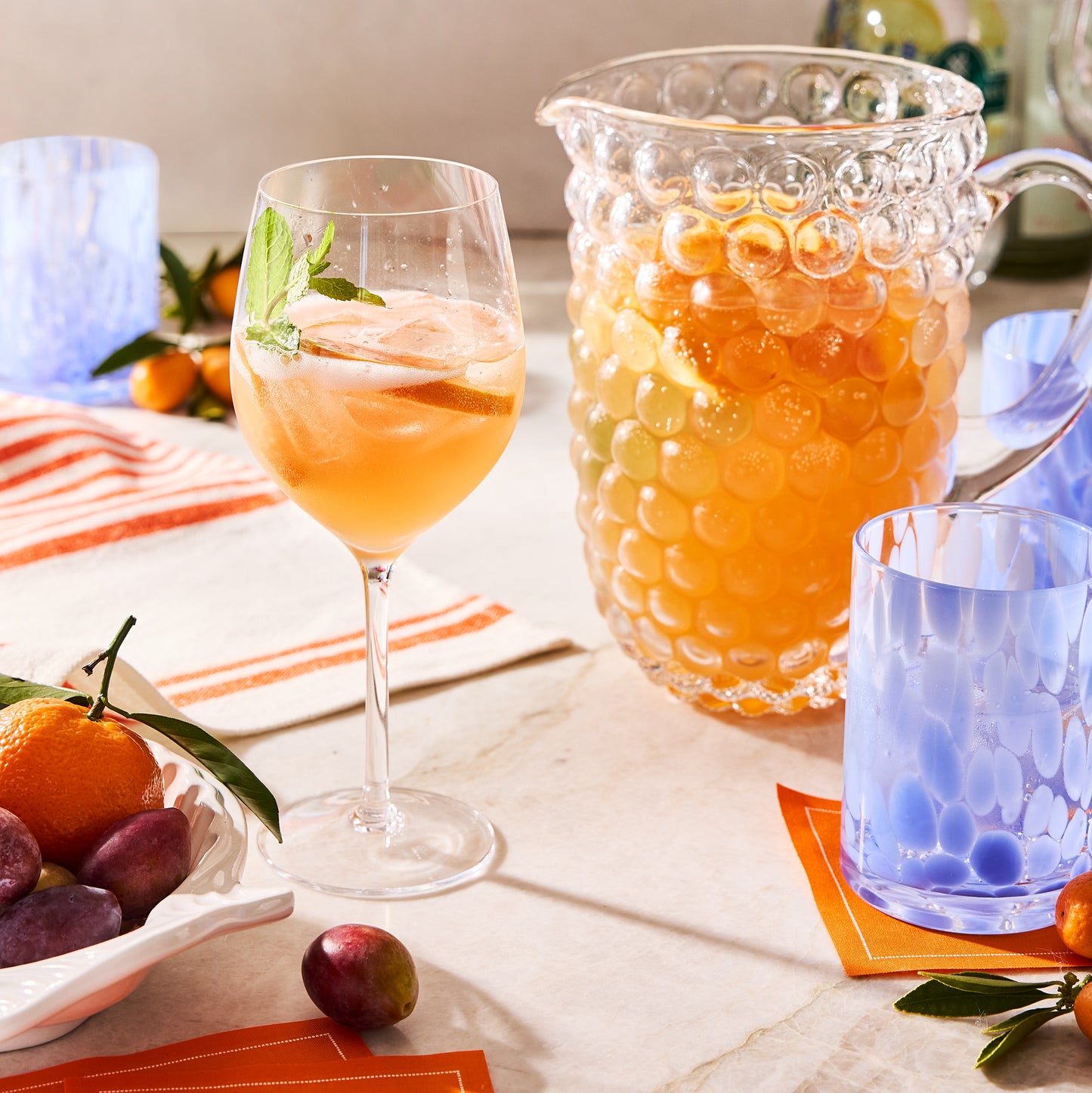 Orange tear-off cotton cocktail napkin roll, partially visible under a blue glass.
