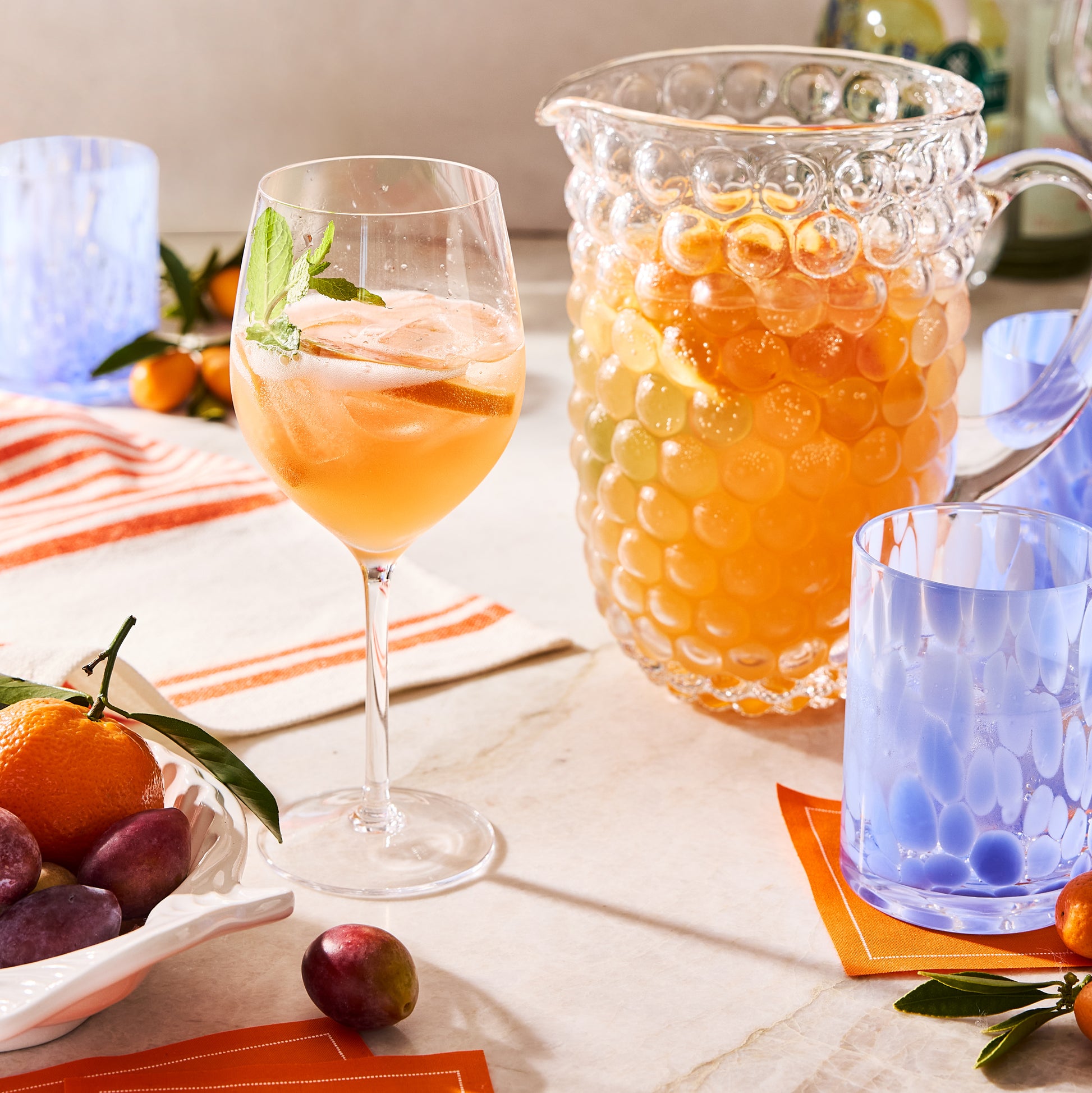 Orange tear-off cotton cocktail napkin roll, partially visible under a blue glass.