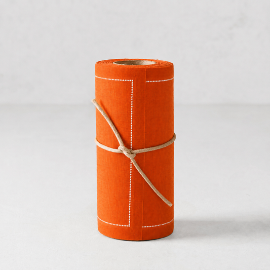 An orange roll of paper or fabric with white stitched border lines and tied with a natural jute string, set against a light gray background.
