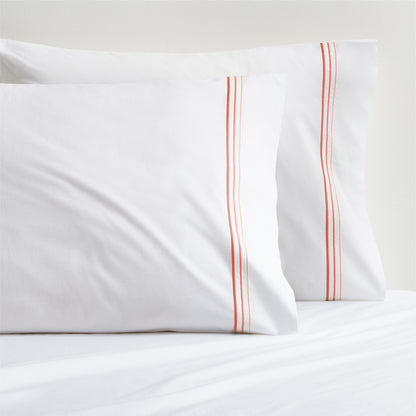 White percale pillowcases with orange ombre triple stitch embroidery.
