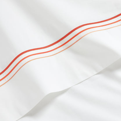 White percale sheet with three ombre orange embroidered stripes.