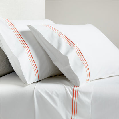 White percale sheet set with orange triple stitch embroidery on pillowcases and flat sheet.