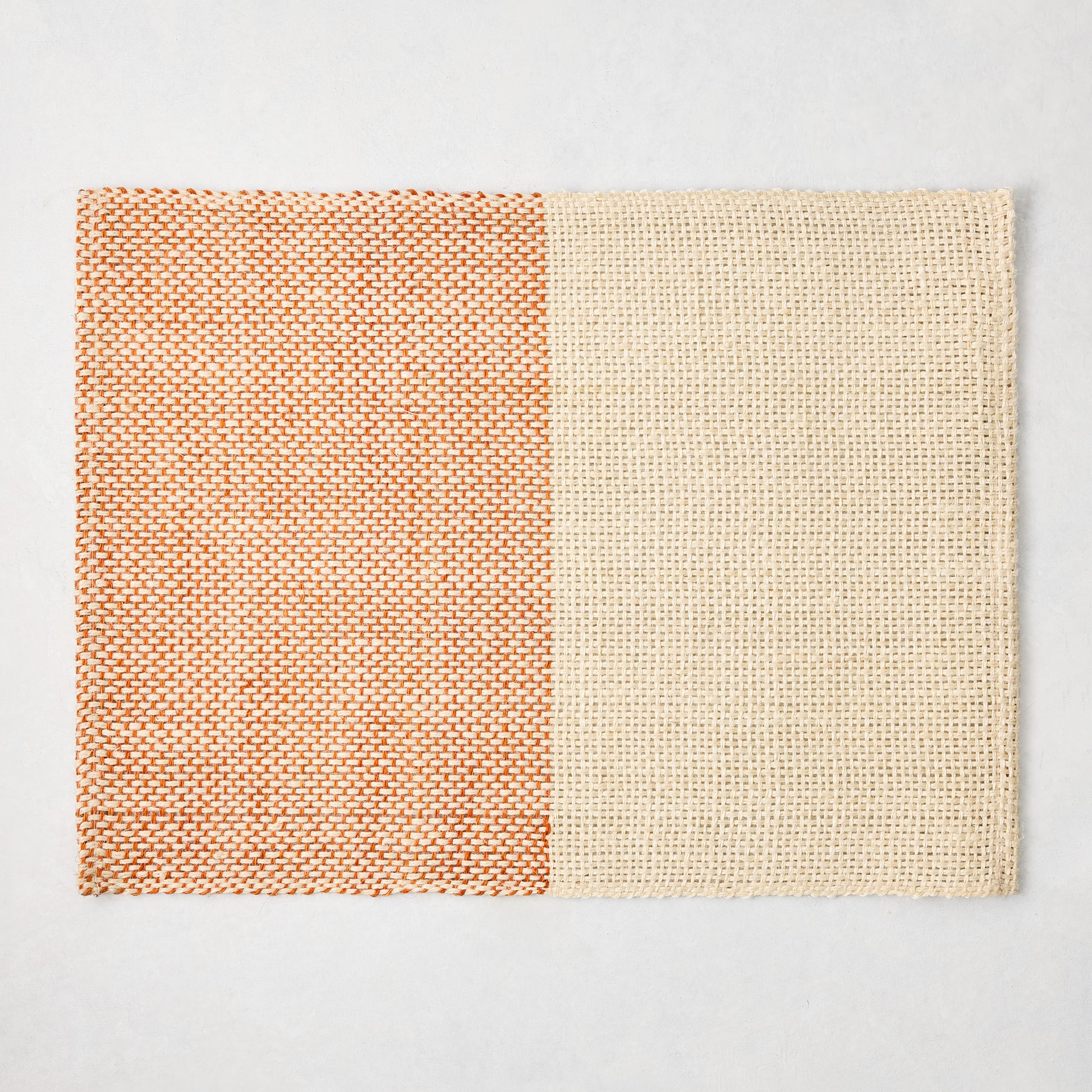 Orange and beige woven abaca and jute rectangular placemat with half and half pattern, 19"W x 14"L.