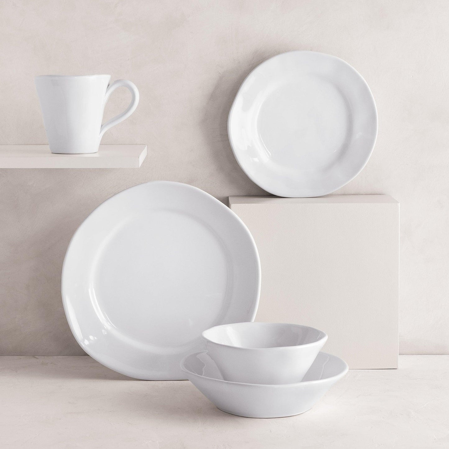 Creamy white ceramic dinnerware set: 11.5" dinner plate, salad plate, mug, and two bowls with organic edges.