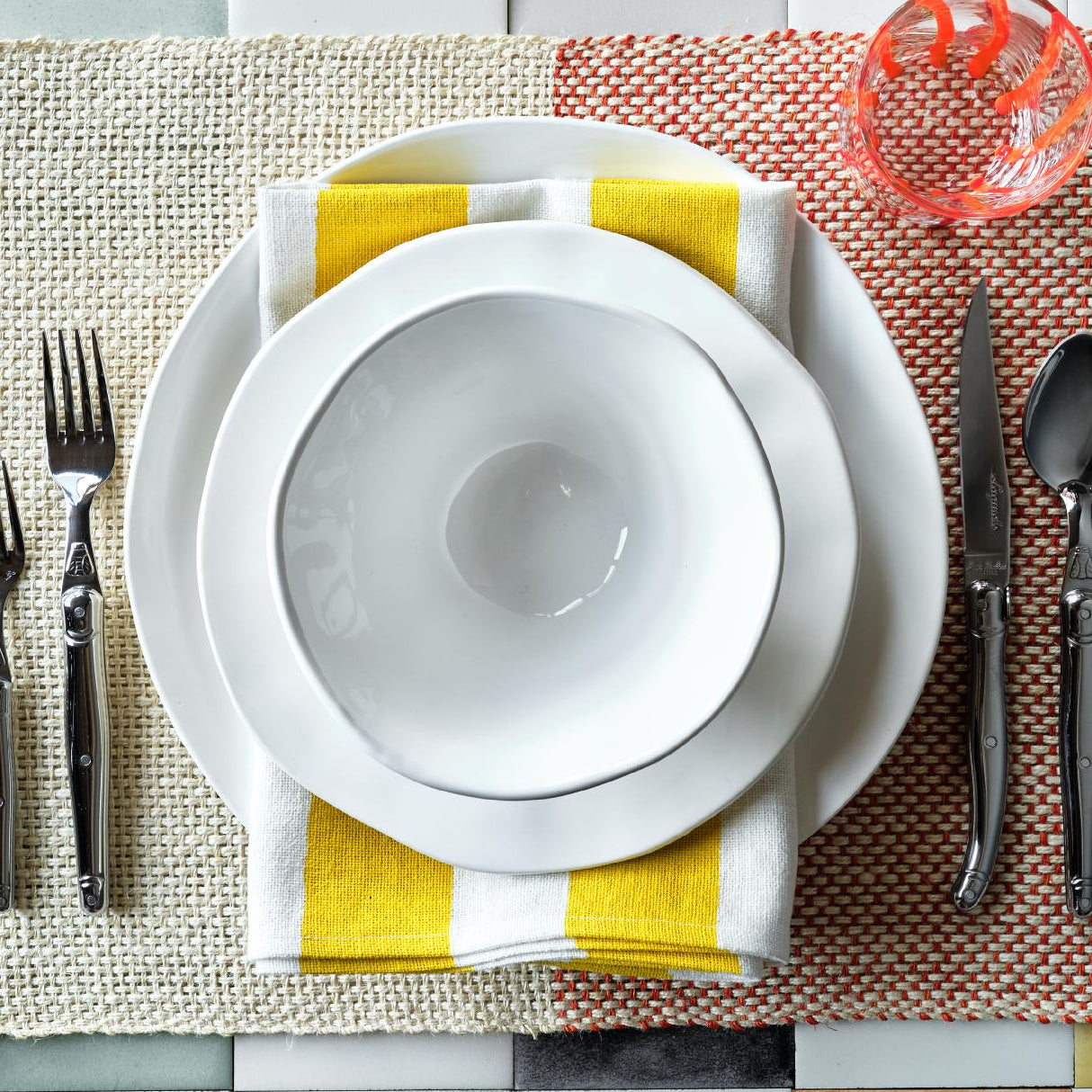 Creamy white organic ceramic breakfast bowl with irregular edges, 6.5 inches in diameter, set on a yellow striped napkin.