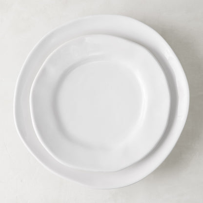 Two white ceramic plates with subtle organic edges, the smaller salad plate on top of a larger dinner plate.