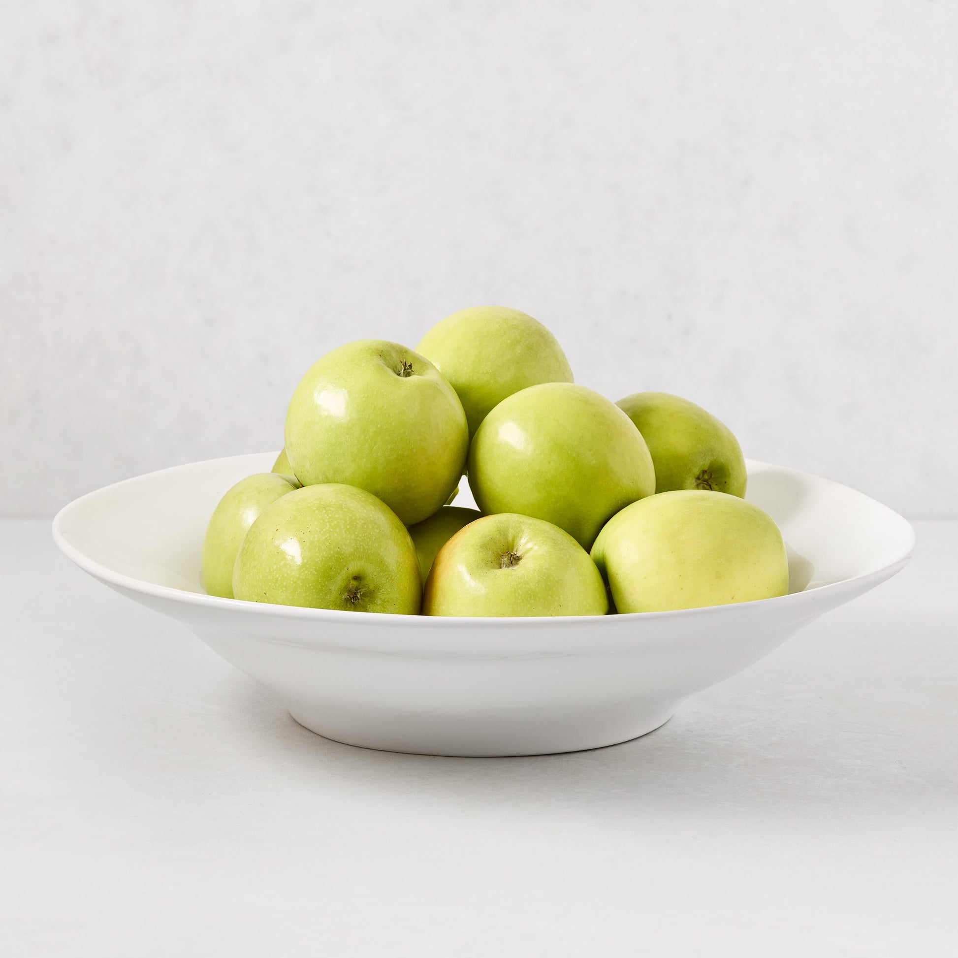 Creamy white Organic Ceramic Serve Bowl, 16" diameter, filled with green apples.