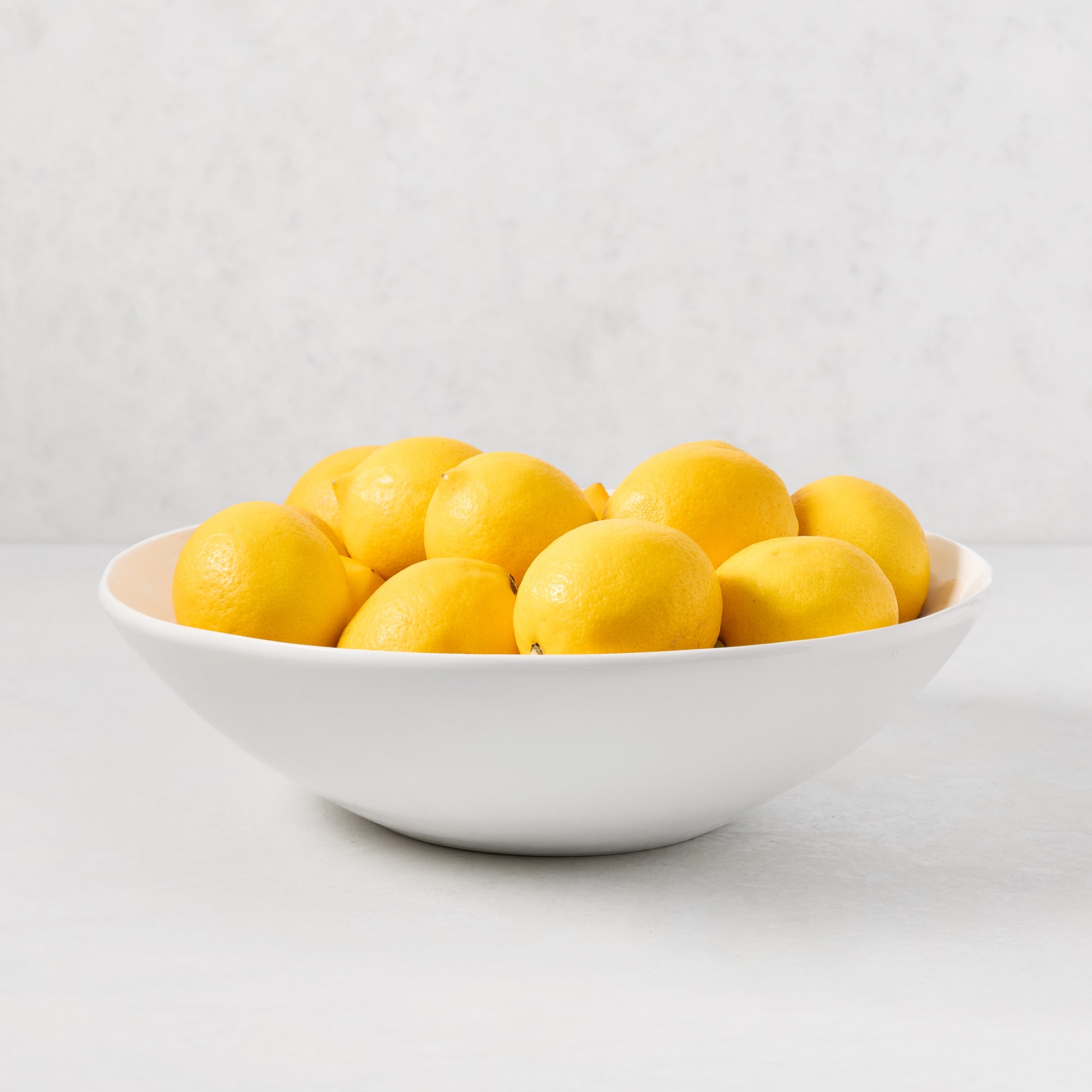 Organic Flared Ceramic Serve Bowl, creamy white, 12" diameter, filled with lemons.