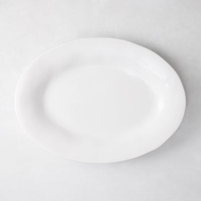 Creamy white oval ceramic serving platter with subtle organic edges.
