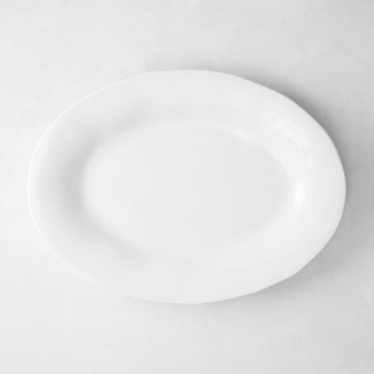 Creamy white oval ceramic serving platter with subtle organic edges.