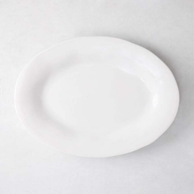 Creamy white oval ceramic serving platter with subtle organic edges.
