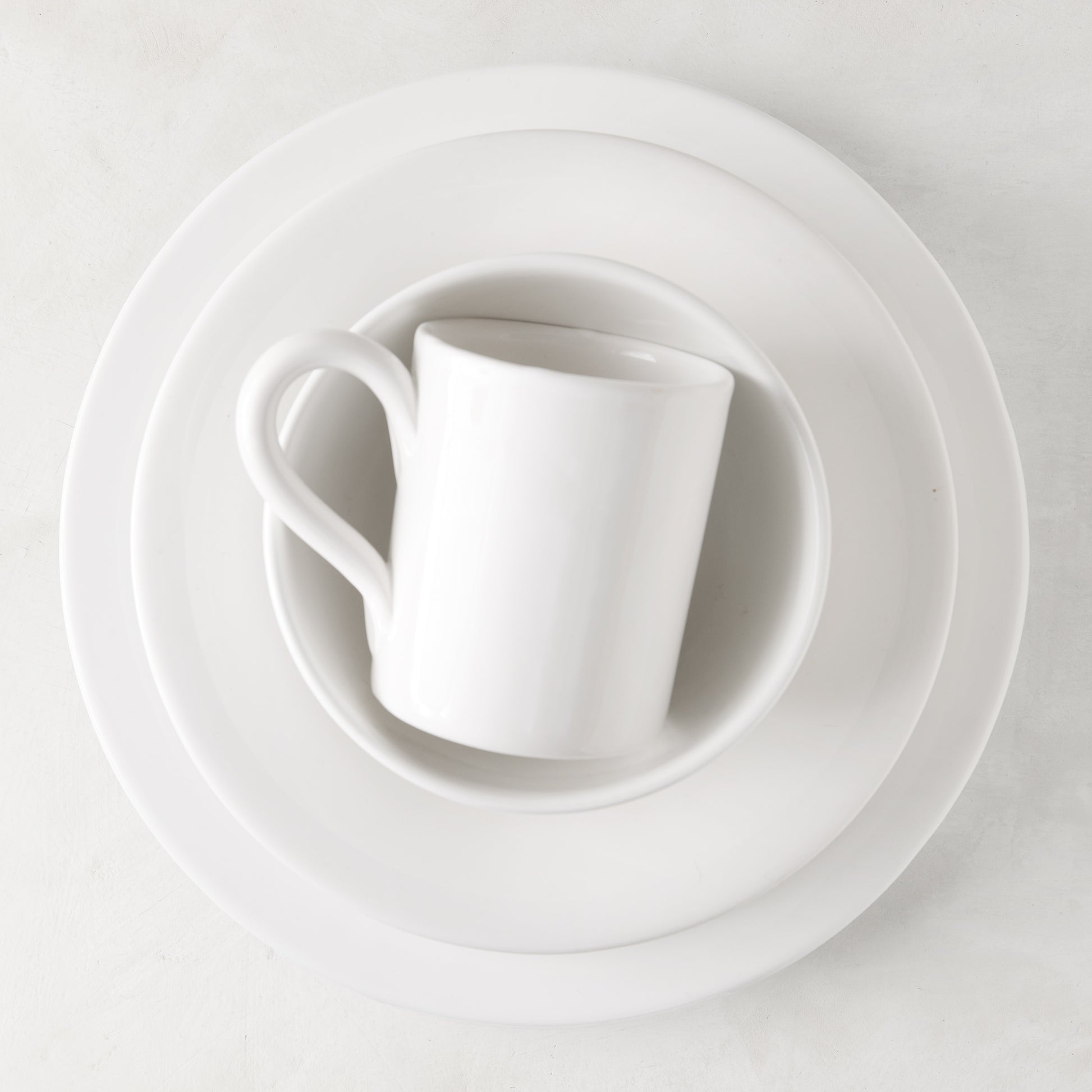 HG Original creamy white ceramic mug, 4" diameter, on stacked white plates.