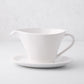Oversized white stoneware gravy boat with handle, spout, and attached plate.