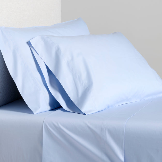 Oxford Blue Italian Percale Sheet Set: light blue cotton flat sheet and two pillowcases on a bed.