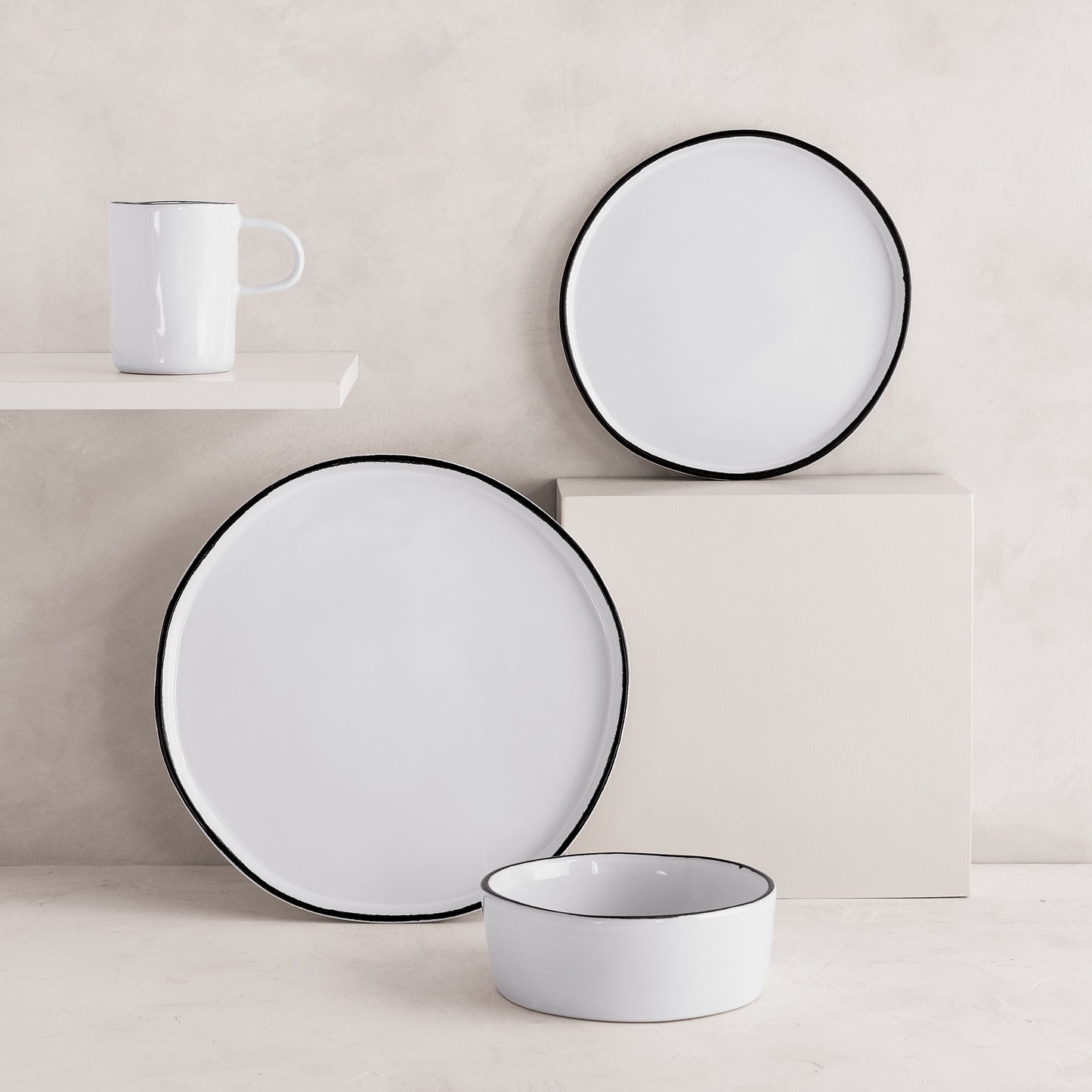 White stoneware mug, dinner plate, salad plate, and bowl with black rims from the Pacific collection.