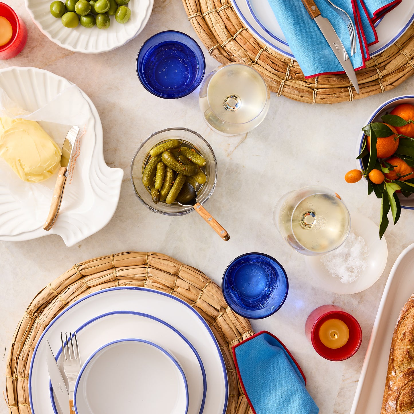 Pacific Blue-Rimmed Stoneware Soup Bowl with white dinnerware, blue napkins, and drinks on a woven placemat.