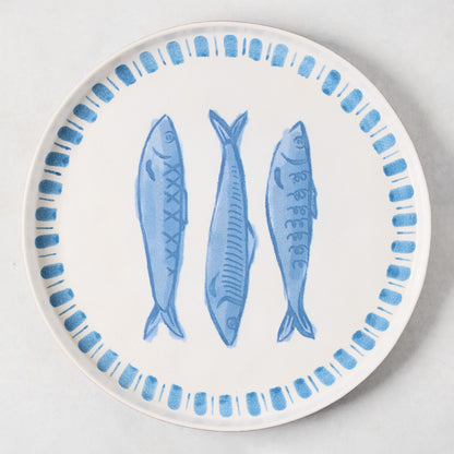 White terracotta round serving platter with three hand-painted blue sardines and a blue border.