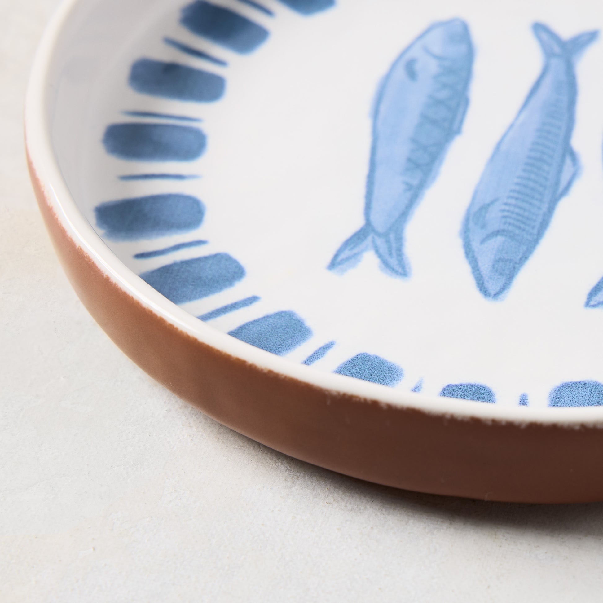 White terracotta salad plate with blue hand-painted sardine and stripe design.