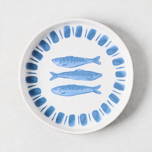White terracotta salad plate with hand-painted blue sardines and a blue striped rim.
